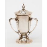 An Arts and Crafts silver pepper pot, pedestal cup form with three sinuous handles,