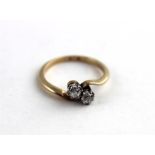 A diamond and 9ct. gold crossover ring, twin diamonds, each approx. .05 carat, claw mounted on