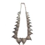 A white metal necklace, formed as graduated and overlapping leaves, each having finely hammered