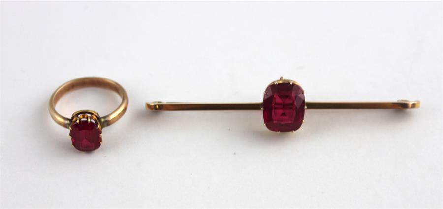 A synthetic ruby and yellow metal bar brooch and a similar matching ring, (both assessed as