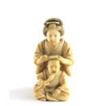 ***AWAY - LONDON*** A Japanese Meiji period ivory netsuke of a mother combing her child's hair, late