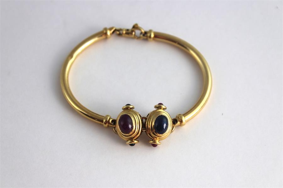 An 18ct gold bracelet set with sapphire and ruby cabochons, having twin stepped oval gold mounts,