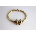 An 18ct gold bracelet set with sapphire and ruby cabochons, having twin stepped oval gold mounts,