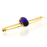 A black opal and 9ct gold bar brooch, the black opal displaying blue and green play of colour,