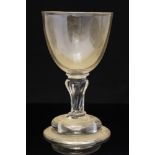 An 18th century wine glass, the rounded bowl on a fluted inverse baluster stem and domed foot,