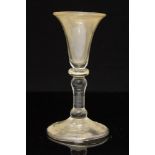 An 18th century wine glass, the trumpet bowl on blade knopped baluster stem and folded foot,