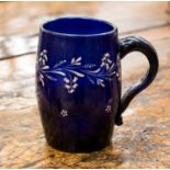 An 18th century Bristol blue mug, barrel form with applied handle, enamelled in white,