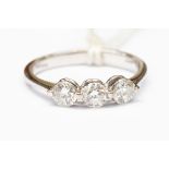 An 18ct white gold three stone diamond ring, with overlap claw setting,