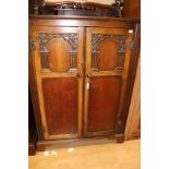 An early 20th Century Jacobean style oak three piece bedroom suite, comprising two door wardrobe,