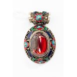 An oriental pendant, in white metal, enamel and a large oval red paste stone, markings to reverse,