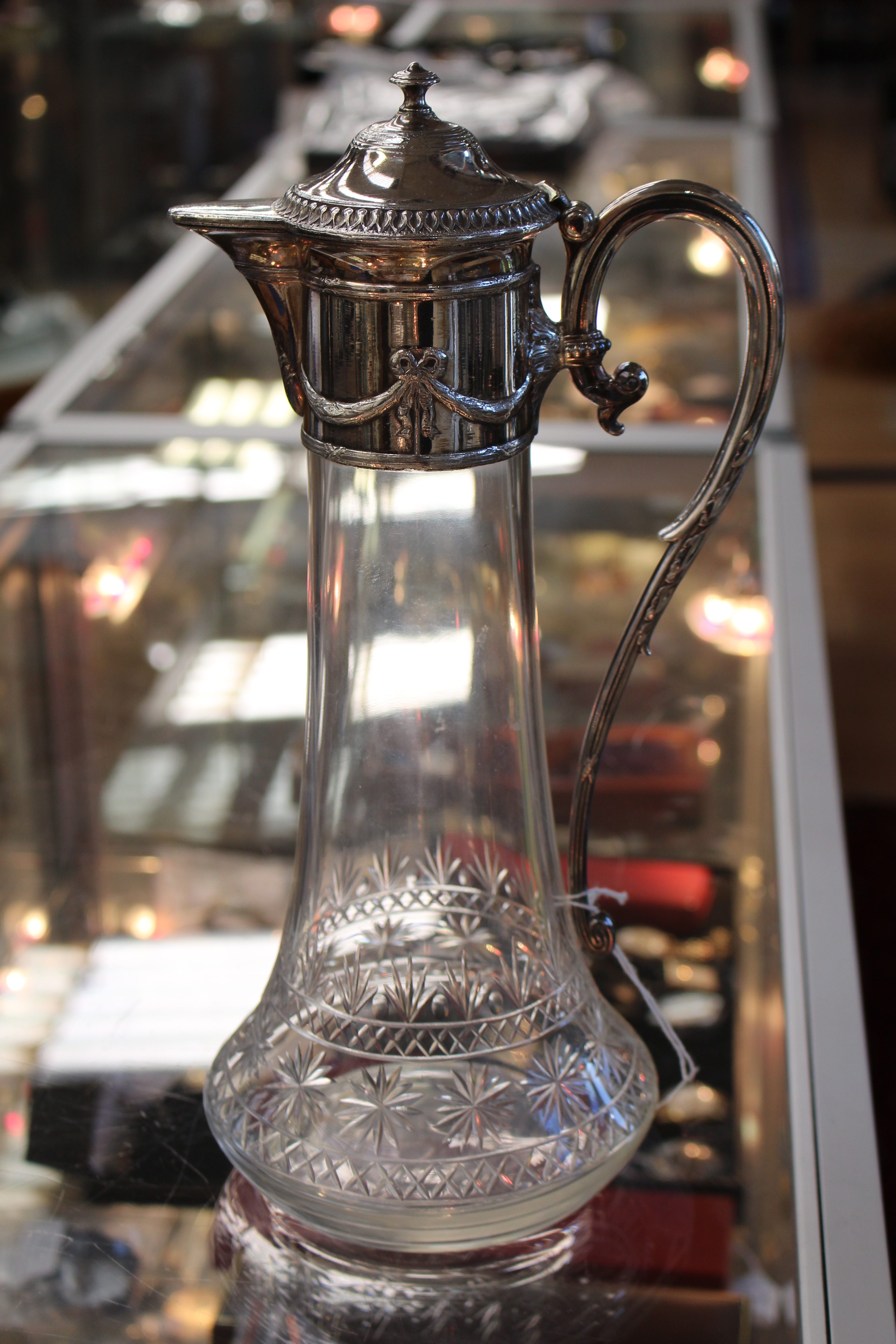An Edwardian silver plated cut glass claret jug, the silver plated mount with swag decoration,