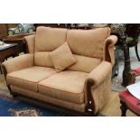 A traditional two seater settee, in salmon pink with floral pattern,