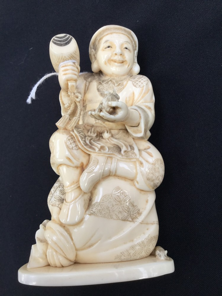 A Japanese Meiji period carved Ivory okimono of a seated smiling man holding a rat,