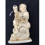 A Japanese Meiji period carved Ivory okimono of a seated smiling man holding a rat,