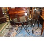 A pair of black aluminum garden chairs and a glass topped aluminum framed table,