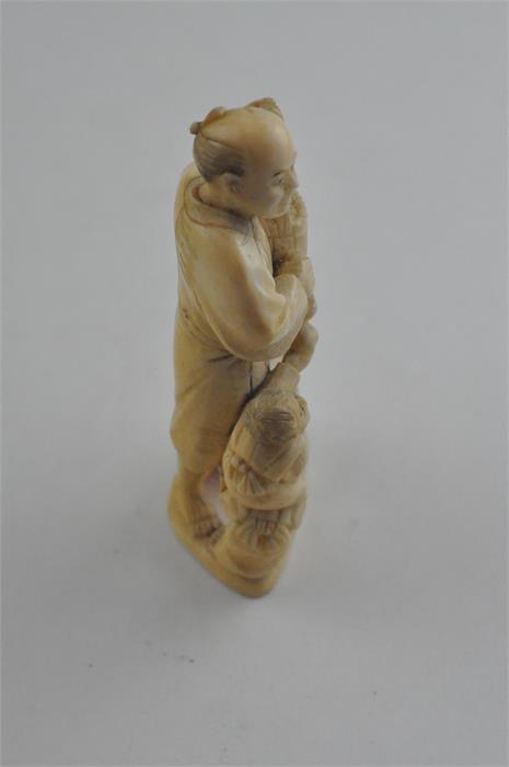 A Japanese Meiji period carved ivory okimono, of a man carrying a basket of fruit with children to - Image 4 of 6