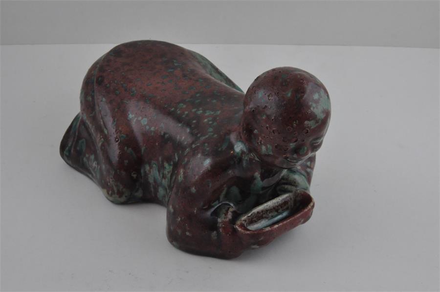 A Chinese high fired boy pillow rest, probably Republic Period. Approx 25cms long x 17cms high.