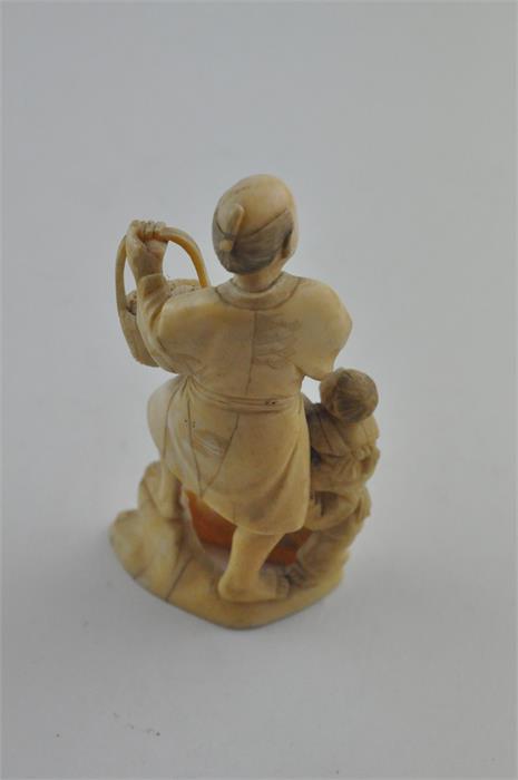 A Japanese Meiji period carved ivory okimono, of a man carrying a basket of fruit with children to - Image 3 of 6