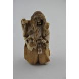 A Japanese Meiji period carved ivory okimono, of a long haired man wearing traditional costume and