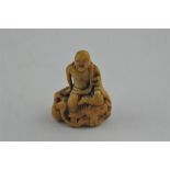 An early Japanese Edo period carved ivory netsuke, of a smiling and seated long haired man. Height 5