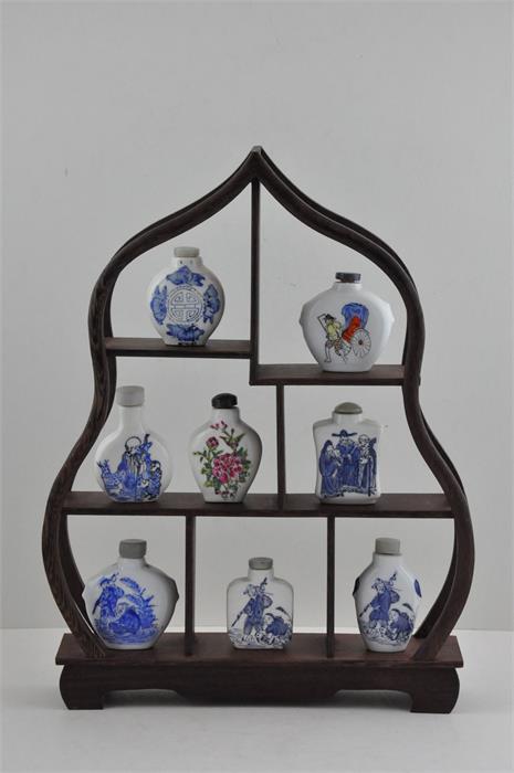 Eight 20th cent Chinese republic snuff bottles on a wooden stand (9 items total)