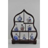 Eight 20th cent Chinese republic snuff bottles on a wooden stand (9 items total)
