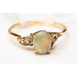 An opal and diamond ring, comprising an oval opal with cross over diamond set shoulders,