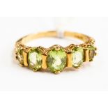 A peridot and 9ct gold dress ring stone ring, claw set with graduated oval peridot stones, size N,