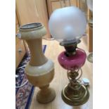 An electrified oil lamp, brass base, pink glass reservoir,