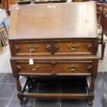 An early 20th Century oak bureau, the fall front enclosing a fitted interior,