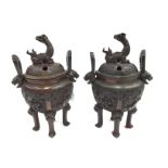 A pair of Oriental bronze censors, relief moulded with Dragons,