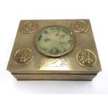 A brass cigarette box, balsa wood lined with a carved jade central disc,