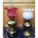 A brass Art Nouveau style brass oil lamp with cranberry coloured etched shade and another with pink