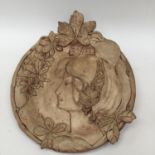 Terracotta Art Deco style wall plate, raised decoration of woman's head, surrounded with leaves,