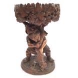 A late 19th / early 20th Century black forest carving of a man by a tree stump,