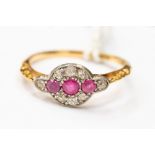 An Edwardian 18ct gold ring, set with three rubies, with a surround of diamond chips, size P,