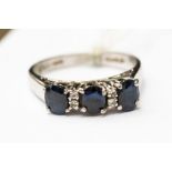 A platinum and sapphire ring set with three oval sapphires, with two small diamonds between each,