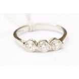 An 18ct white gold three stone diamond ring, with overlap claw setting,