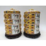 A pair of Chinese ceramic wedding food baskets, each with four tiers and lids on wood stands,