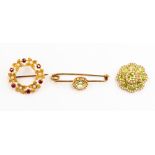 A group of three brooches including a peridot and seed pearl set brooch in yellow metal probably