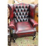 A traditional red leather wing back chair, deep buttoned back,