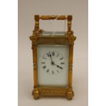 A large brass carriage clock, having Roman numeral white enamel dial, coiled spring gong,