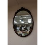 A mahogany framed oval mirror with carving to top (1)