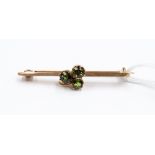 A three stone tourmaline bar brooch, set in the form of a leaf,