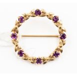 A yellow metal, probably 9ct gold, amethyst brooch, with round stone and interspaced cross detail,