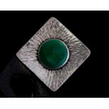 A Modernist silver and enamel brooch, the green cabochon within a planished square ground,
