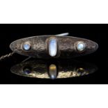 An Arts and Crafts white metal and moonstone brooch, lozenge form with three cabochon stones,