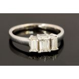 A diamond and platinum three-stone ring, claw set with a rectangular cut diamond,
