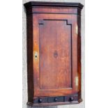 A George III oak hanging corner cupboard, the single door enclosing fitted shelves,