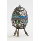 A Russian silver gilt and cloisonné enamelled egg, on three cast hoof legs,